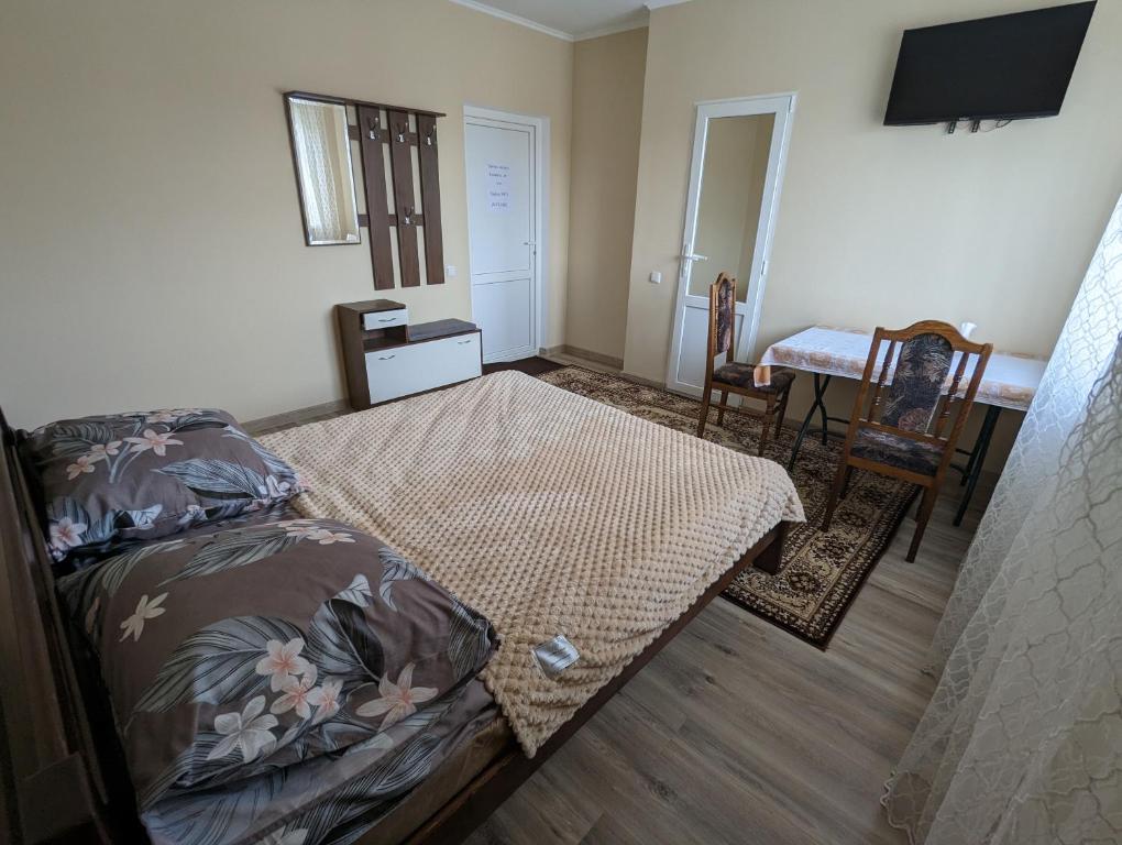 een slaapkamer met een bed en een tafel en stoel bij Гостиный дом 