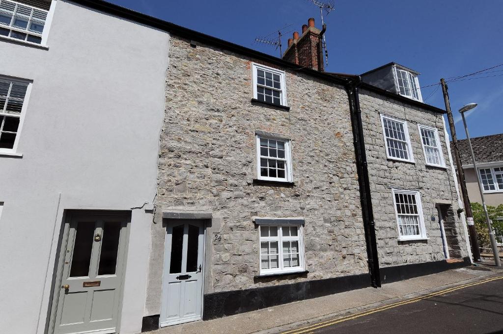 un edificio de piedra con puertas blancas y ventanas en una calle en 24 Mill Green, en Lyme Regis