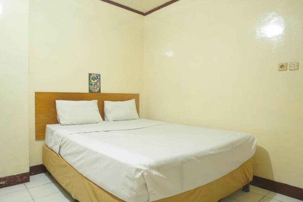 a bedroom with a large bed with white sheets at SPOT ON 92549 Wisma Ribas Syariah 