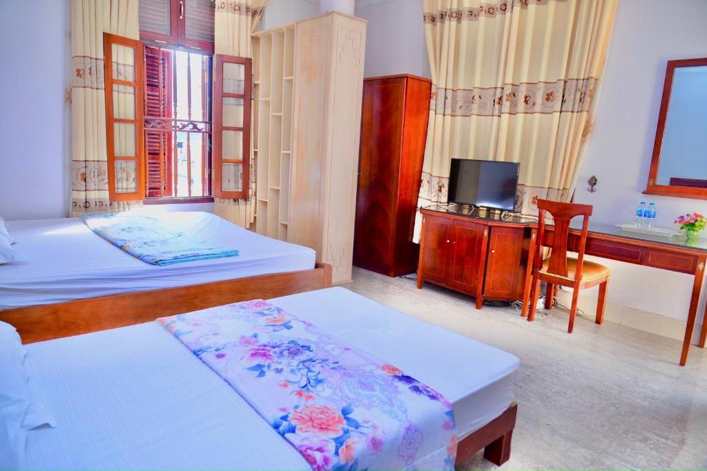 Móng CáiにあるThịnh Nhàn motelのベッドルーム1室(ベッド2台、デスク、テレビ付)
