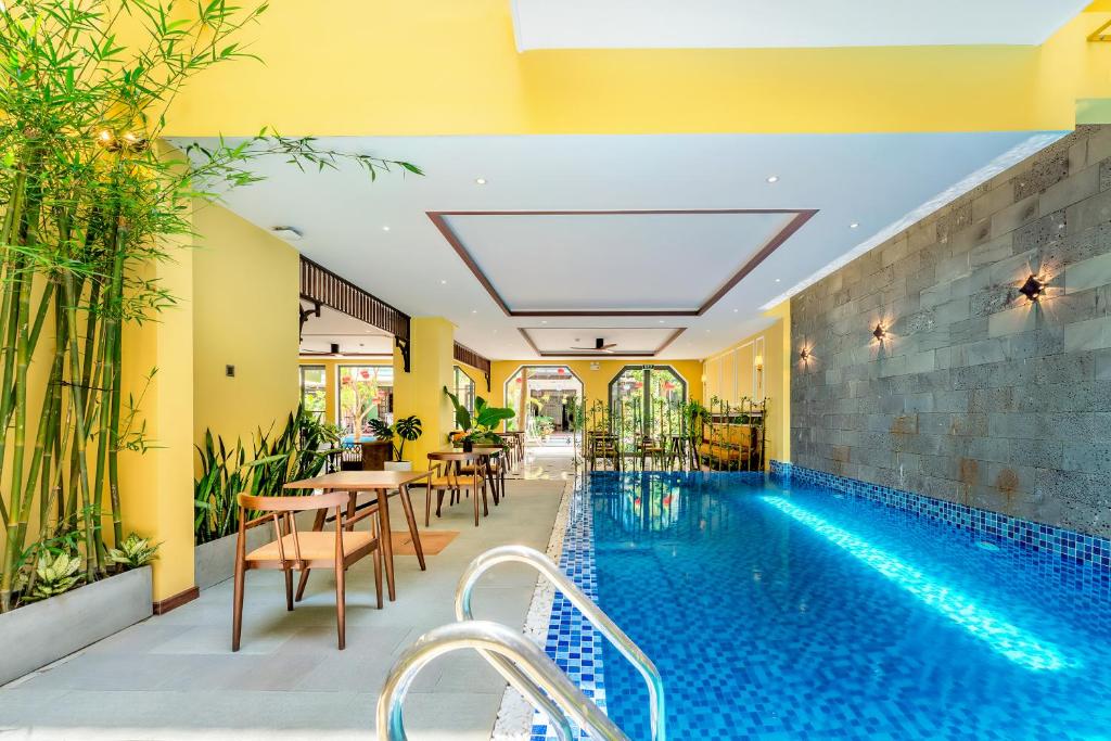 a pool in a hotel with tables and chairs at Chillax Old Town Villa in Hoi An