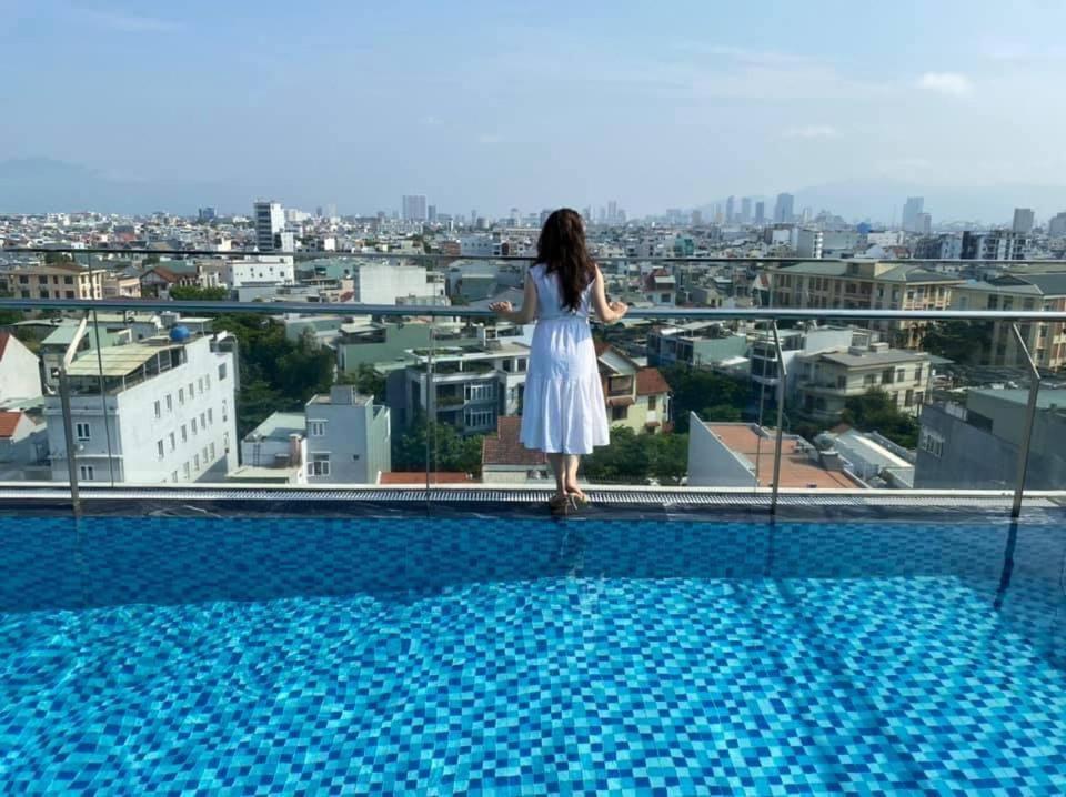 a woman in a white dress standing on the edge of a building at Minh Quan Hotel - Da Nang Center By HOS in Da Nang