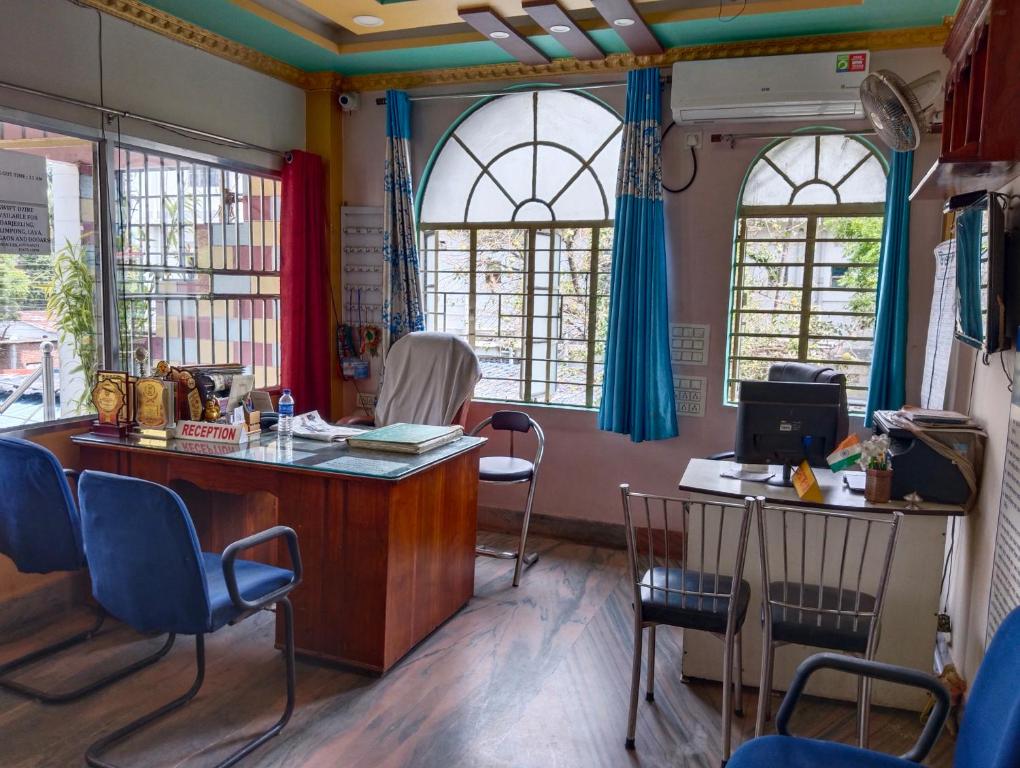 Bikash Bhawan Lodge في سيليغري: غرفة انتظار مع كراسي ومكتب ونوافذ