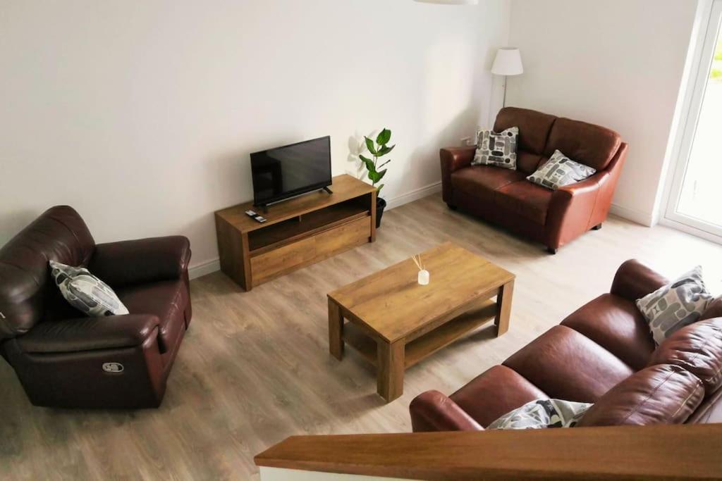 a living room with leather furniture and a tv at Secluded Modern Guest House in Castletown Gheoghegan