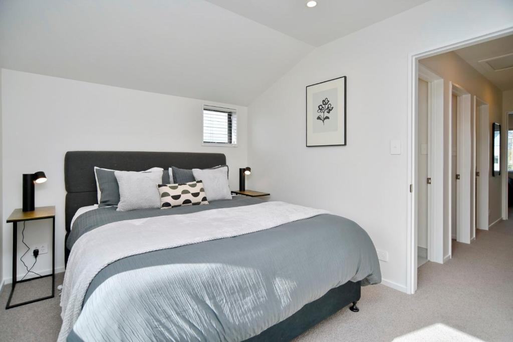 a white bedroom with a large bed in it at Āta Haere - Christchurch Holiday Homes in Christchurch