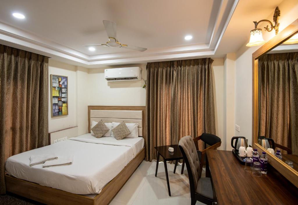 a bedroom with a bed and a desk and a table at M Square Hotel in Hyderabad