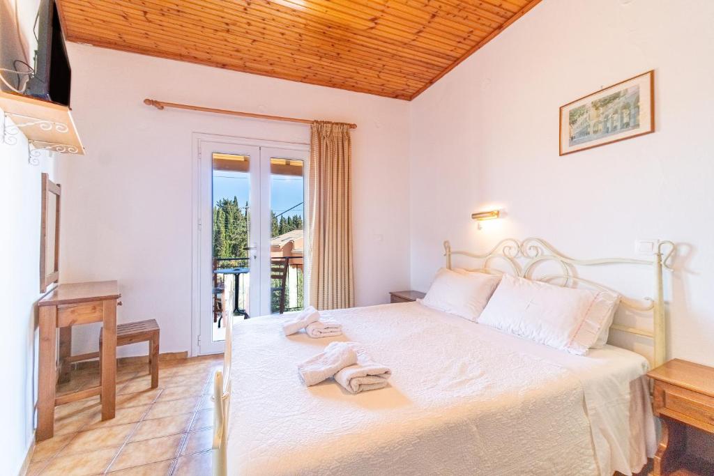 una camera da letto con un grande letto bianco e una televisione di Korina Studios a Paleokastritsa