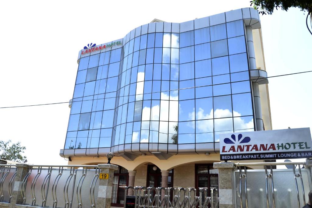 un grand bâtiment en verre avec un panneau devant lui dans l'établissement Lantana Hotel, à Dar es Salaam