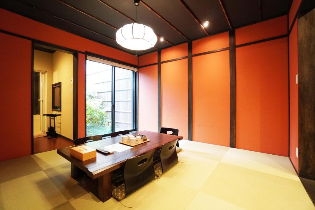 ein Esszimmer mit orangefarbenen Wänden und einem Holztisch in der Unterkunft MUSUBI Sanjo Bettei in Shimo-dachiyuuridōri