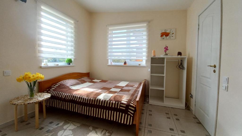 um pequeno quarto com uma cama e 2 janelas em SweetHome em Limbaži