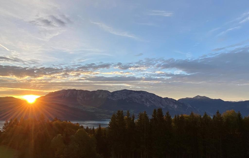 a view of the sun setting over a mountain range at Appartmens am Attersee Dachsteinblick in Nussdorf am Attersee