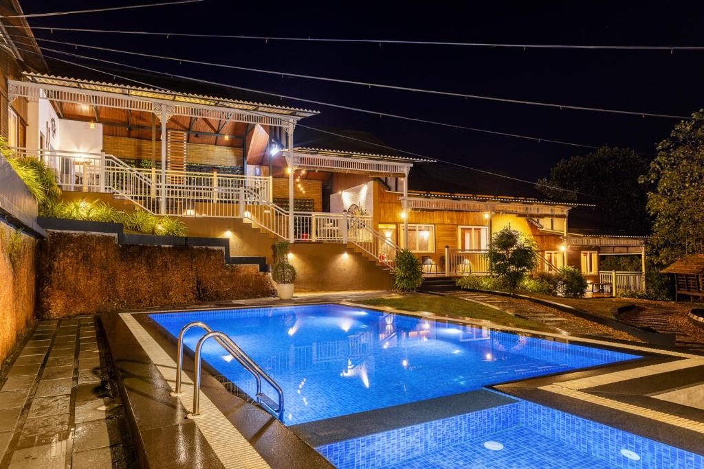 a swimming pool in front of a house at night at Johns Village in Cochin