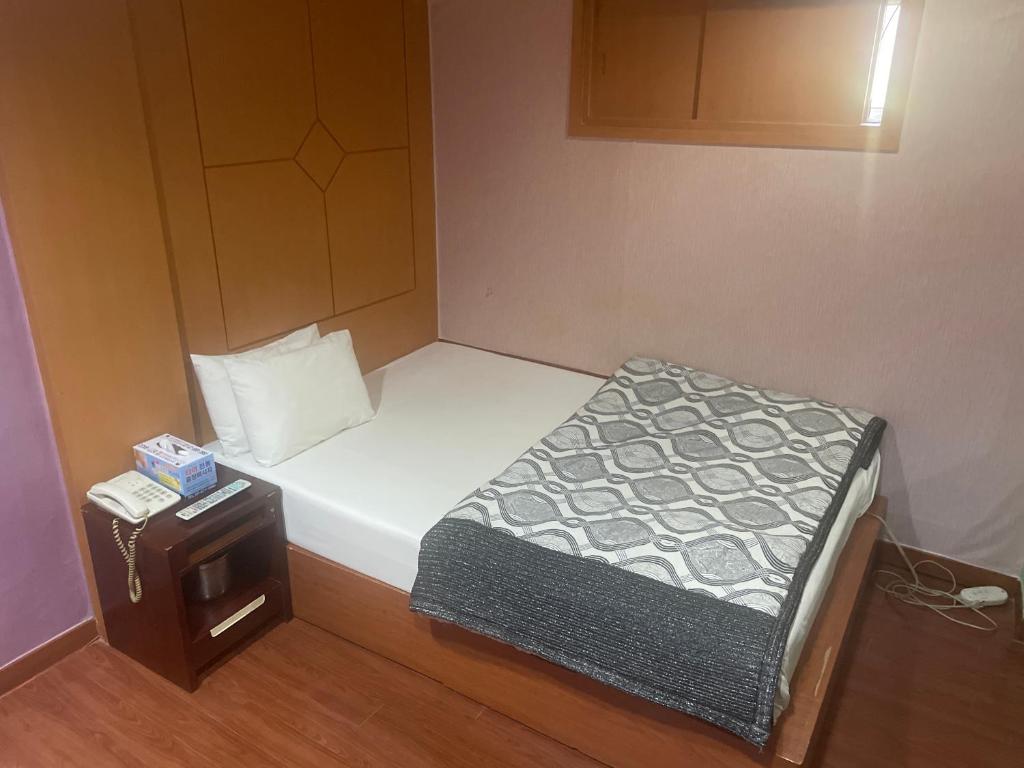 a small room with a bed and a night stand at Grace Motel in Seoul