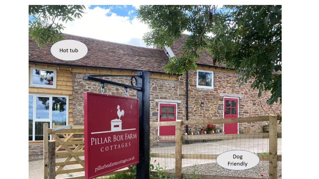 um sinal em frente a um edifício de tijolos em The Hayloft, Pillar Box Farm Cottages em Ludlow