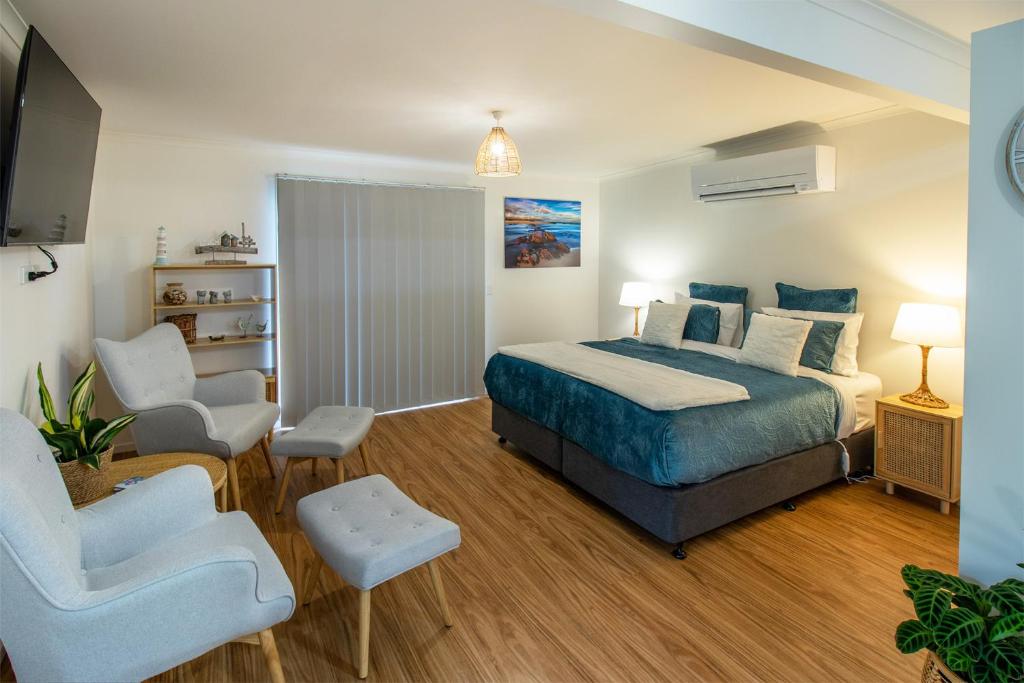 a bedroom with a bed and two chairs and a tv at Coola studio in Mallacoota