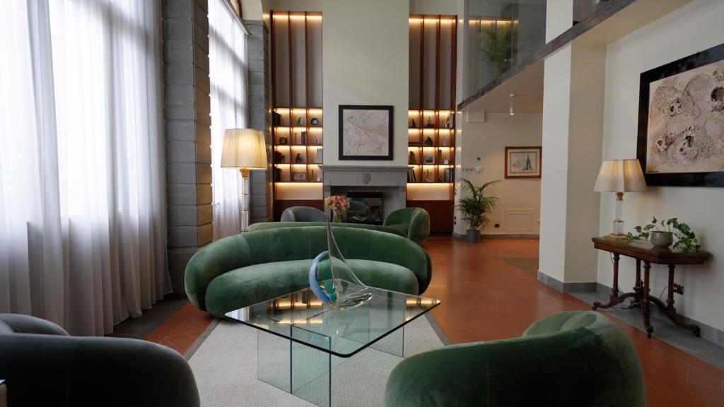 a living room with green chairs and a fireplace at Hotel Kraft in Florence