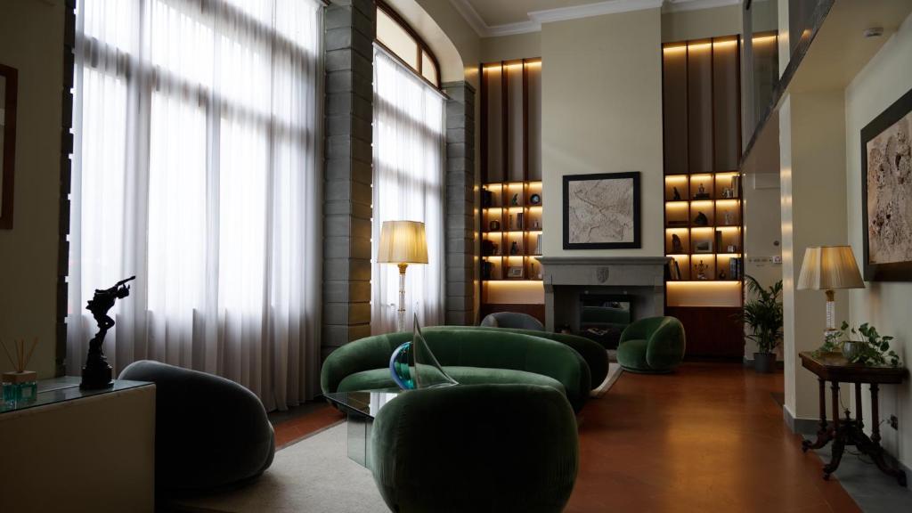 a living room with green chairs and a fireplace at Hotel Kraft in Florence