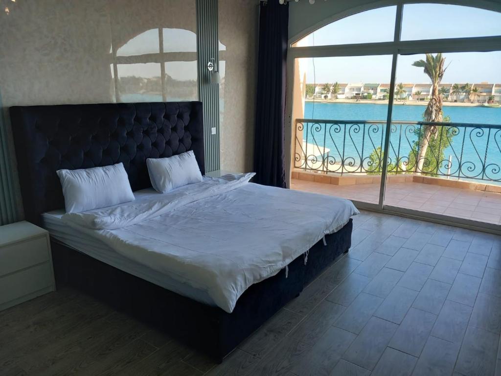 ein Schlafzimmer mit einem großen Bett und einem Balkon in der Unterkunft فيلا بلوبيتش بمسبح خاص وشاطى رملي in Durrat Al-Arus