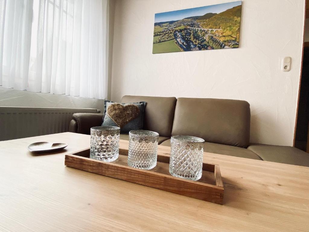 a table with three glasses on a wooden tray at FEWO Vanessa in Willingen