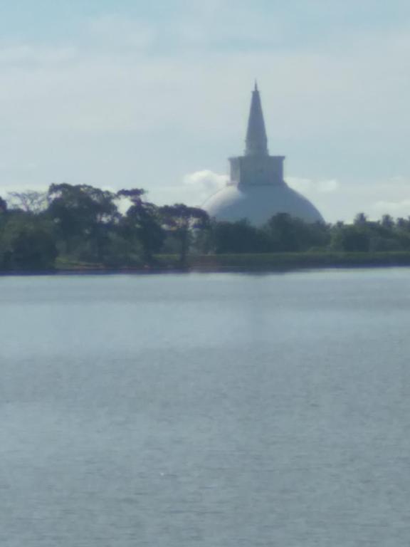 a large body of water with a building in the background at Chathuni Holiday Home in Anuradhapura