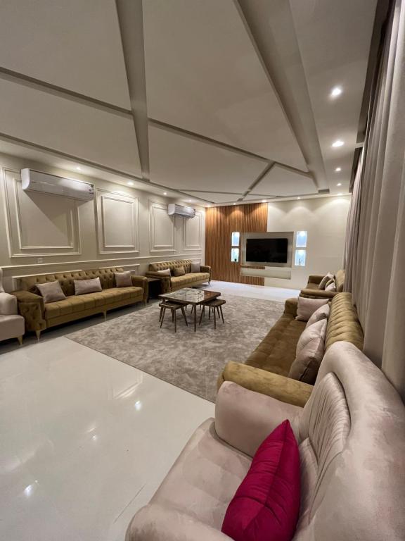 uma grande sala de estar com sofás e uma mesa em شاليه هابي نايت em Al Harazat