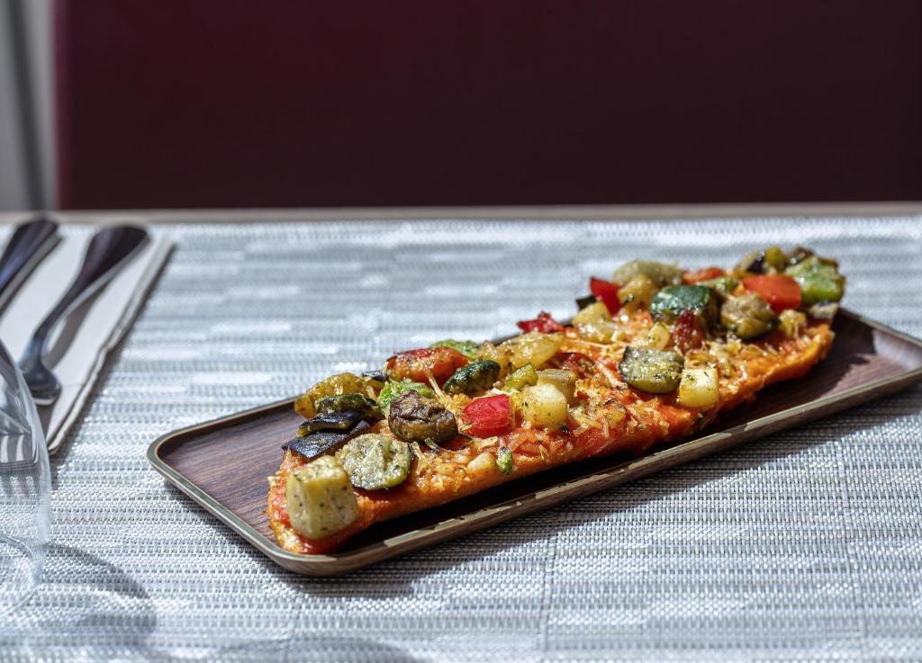 a slice of pizza on a plate on a table at Hotel Ankaa - Adults Only in Porto Cristo