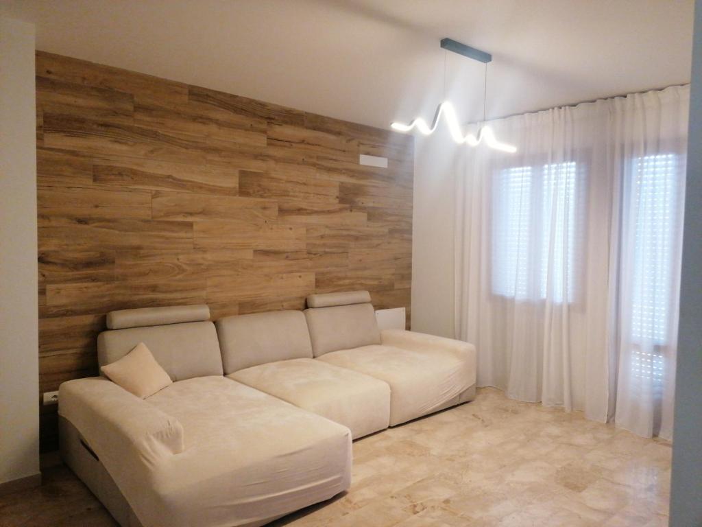 casa a due passi dal centro في بادوفا: أريكة بيضاء في غرفة بجدار خشبي