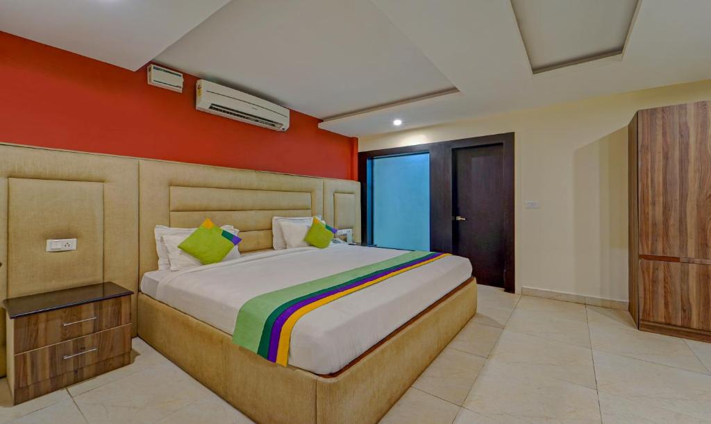 a bedroom with a large bed with orange walls at Treebo Trend Elan in Chennai