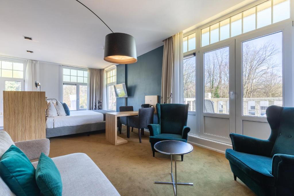 een woonkamer met een bed en een tafel en stoelen bij Amrâth Berghotel Amersfoort in Amersfoort