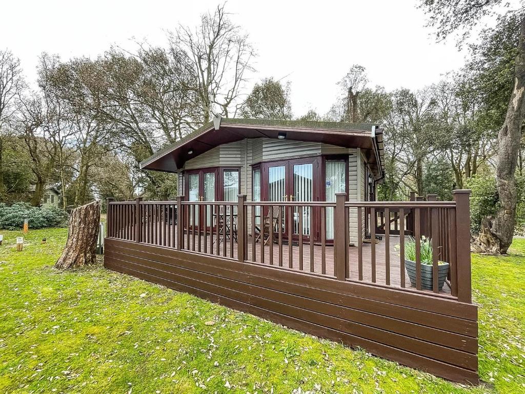 a small cabin with a deck in the grass at Pet Friendly, Luxury Lodge With Decking In Suffolk Near The Beach Ref 32108a in Lowestoft