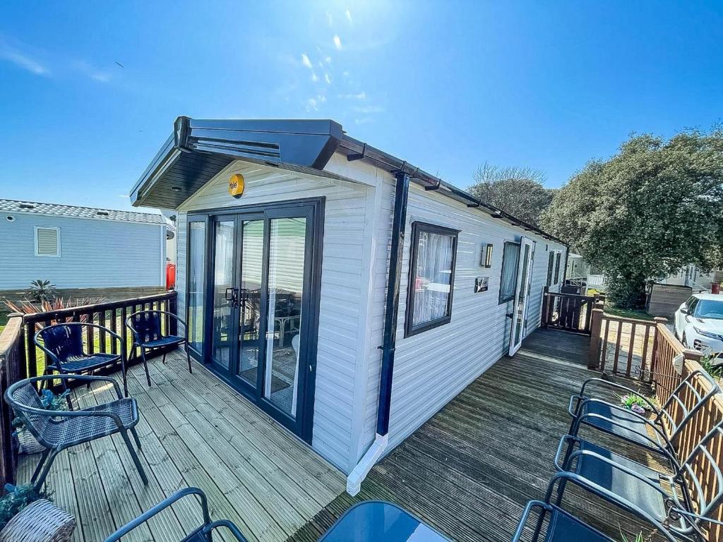 a tiny house on a deck with chairs on it at Beautiful Caravan For Hire With A Partial Sea View In Suffolk Ref 32042az in Lowestoft