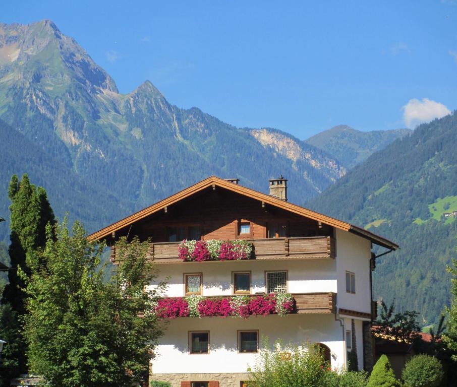 a building with flowers on the balcony with mountains in the background at Haus Schlechter in Mayrhofen