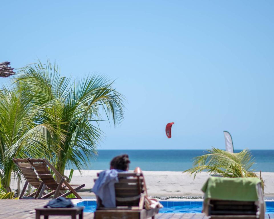 un homme assis sur une chaise à la plage dans l'établissement Kite Lodge Brazil, à Prea