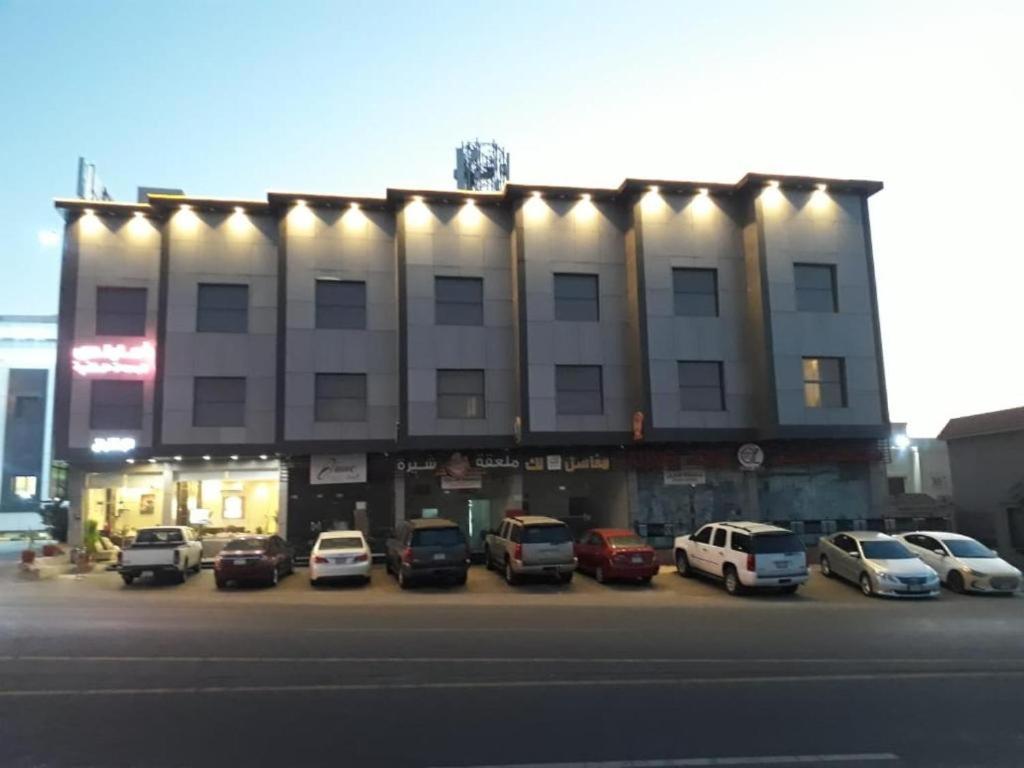 a large building with cars parked in a parking lot at امارلس للشقق الفندقية in Khamis Mushayt