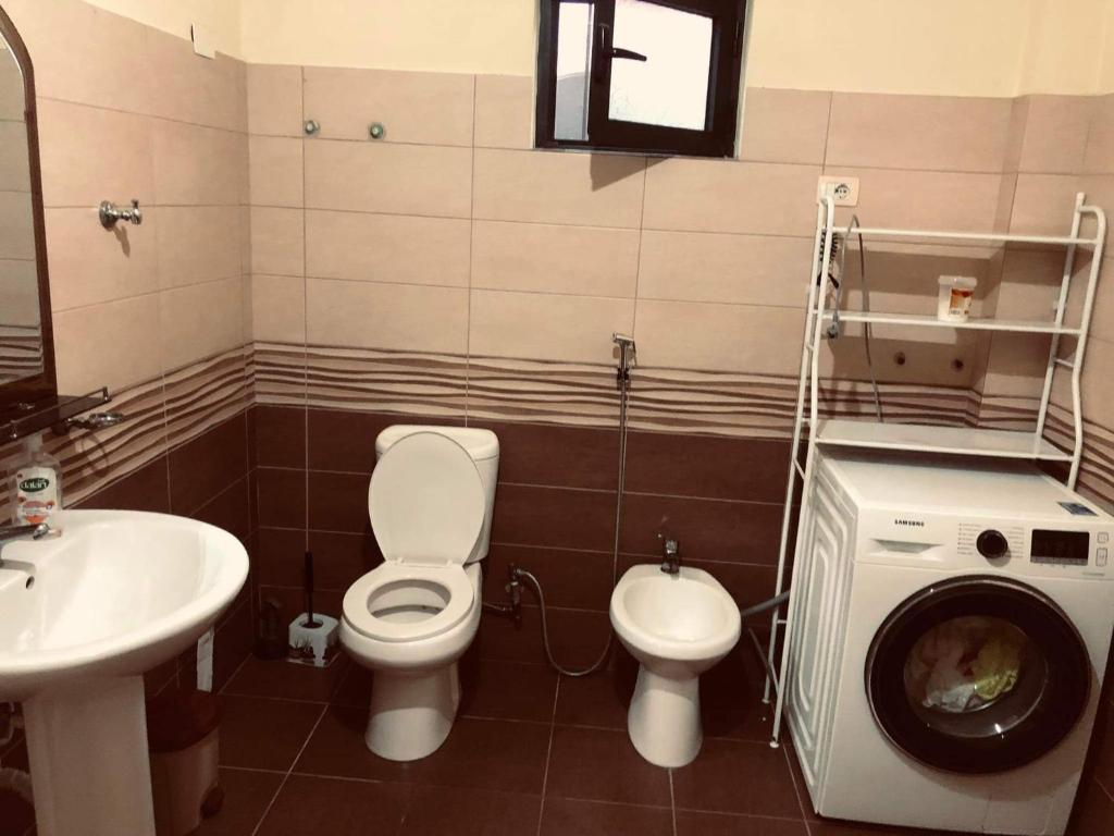 a bathroom with a toilet and a sink and a washing machine at Villa Ceni 3 in Elbasan