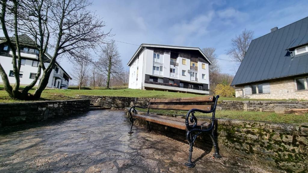 普利特維采湖的住宿－Apartman Filipčić，石墙旁的公园长凳,有房子