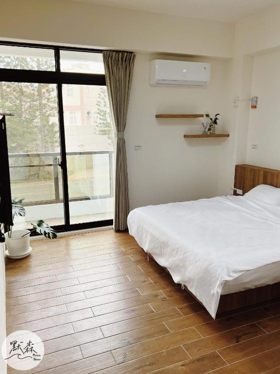 a bedroom with a white bed and a large window at 默森民宿 in Huxi