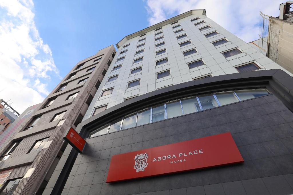 ein hohes Gebäude mit einem roten Schild darauf in der Unterkunft Agora Place Osaka Namba in Osaka