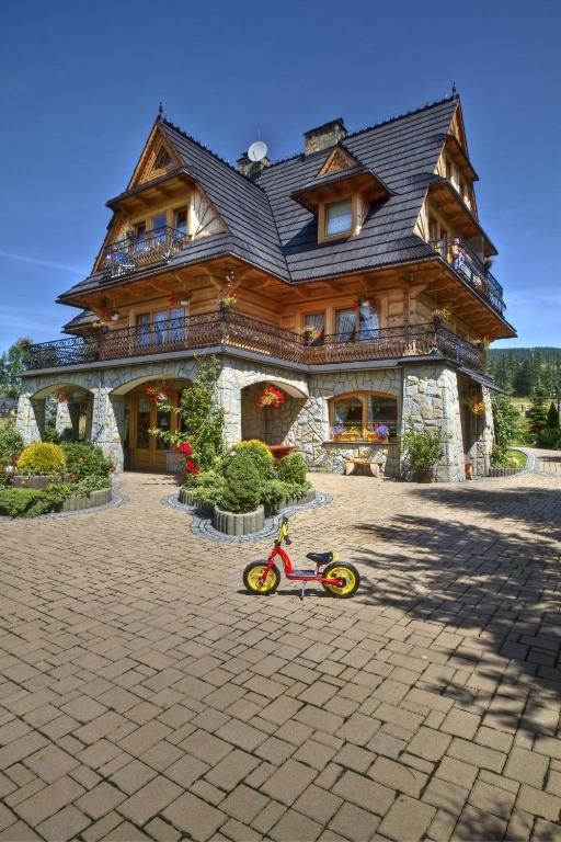 a small red bike parked in front of a large house at Willa Krzesanica in Kościelisko