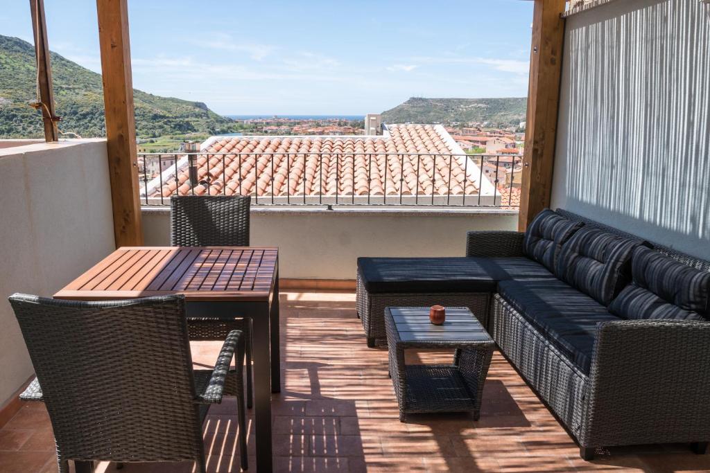 Un balcón con sofá, mesas y vistas. en Belvedere - Terrazza panoramica en Bosa