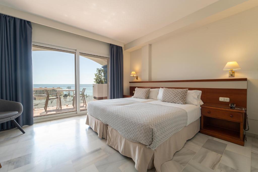 sypialnia z łóżkiem i widokiem na ocean w obiekcie Hotel Piedra Paloma w mieście Estepona