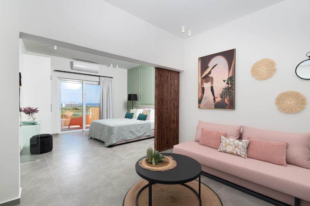 Meliora Suites في Dhrapaniás: غرفة معيشة مع أريكة وردية وسرير