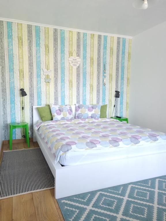 a bedroom with a white bed with a striped wall at Dream Studio Petrosani in Petroşani