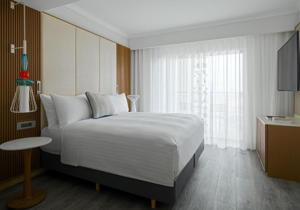 a bedroom with a large white bed and a window at Malta Marriott Resort & Spa in St. Julianʼs
