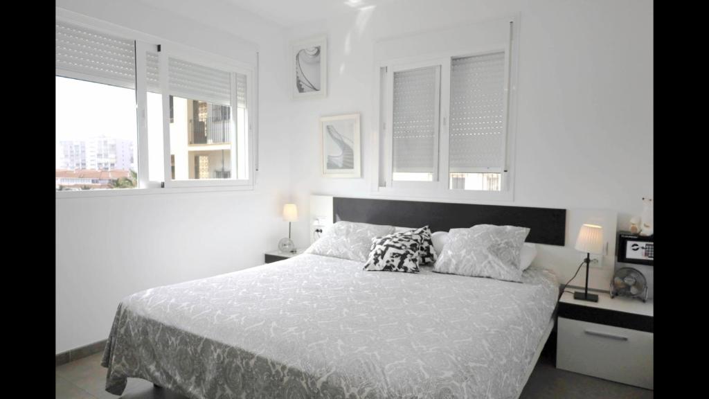 biała sypialnia z łóżkiem z poduszkami i oknami w obiekcie FREDOV w mieście Benalmádena