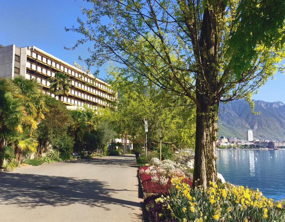 a park with flowers and a building next to a lake at Royal Plaza Montreux in Montreux