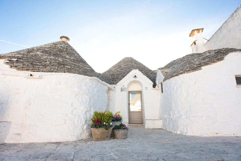 un edificio bianco con due porte e due piante in vaso di Trulli Holiday Deluxe & Wellness ad Alberobello