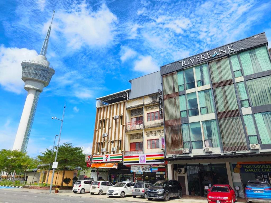 a building with a tower in the background with cars parked at Riverbank Kuantan by Glex in Kuantan