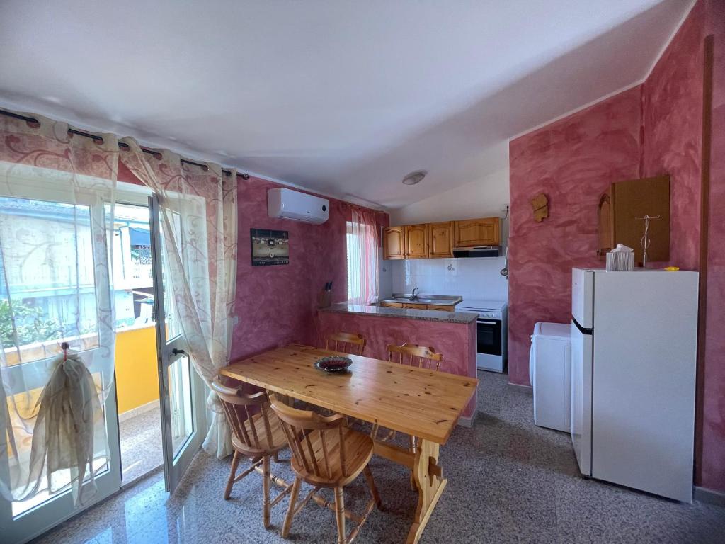 eine Küche mit einem Holztisch und einem Kühlschrank in der Unterkunft Dimora Pina sul mare in Codaruina
