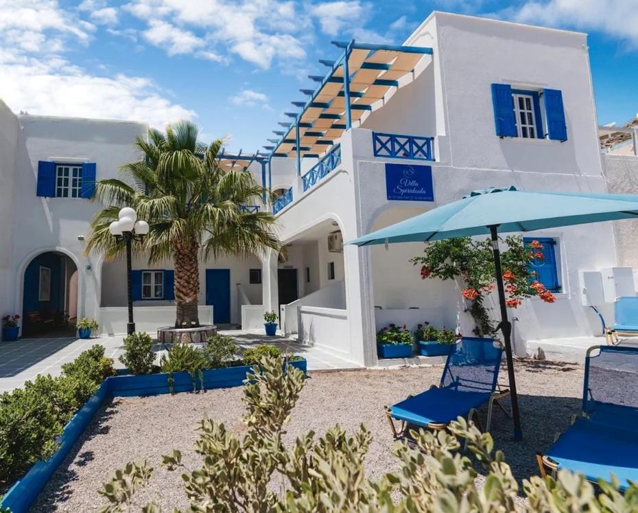 una casa con sillas azules y sombrilla en Spiridoula Villa - Santorini Seaside Retreats, en Perissa